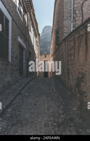 narrow dark empty cobblestone street in spanish town of Biniaraix, Soller amidst historic houses Stock Photo