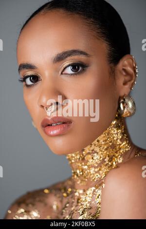 Portrait of pretty african american model with foil on chest and piercing isolated on grey,stock image Stock Photo