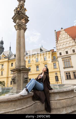 Young woman holding paper cup near Statue of Saint Joseph and fountain in Charles Square in Prague,stock image Stock Photo
