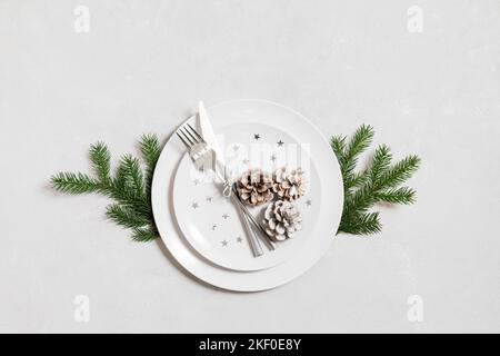 Christmas table setting with a fir branch and cones on a gray background. Copy space, top view, flat lay. Winter Holidays Background Stock Photo