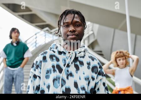 Diverse group of young people wearing street style clothes outdoors focus on black man looking at camera in foreground Stock Photo