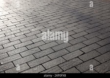 Stone pavement texture, cobbled street in sunlight. Road from tiles for background Stock Photo