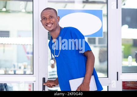handsome young male doctor holding digital tablet in hospital smiling at camera. Stock Photo