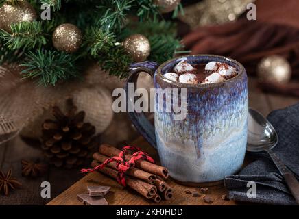 Mug of hot chocolate and marshmallows on a wooden table with Christmas decorations in background Stock Photo
