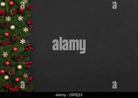 Christmas border with fir branches, red berries and golden snowflakes on black background. Happy new year. Greeting card. Copy space, top view, flat l Stock Photo