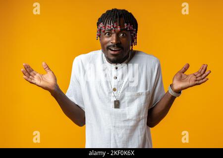 Young afrcian man on yellow background showing helpless gesture with hands Stock Photo