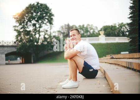 young man talking on a mobile phone, sitting on the steps in the Stock Photo