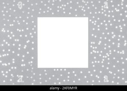 Blank template with silver confetti stars and white paper on a gray background. Festive or Christmas mockup. View from above. Space for text. Stock Photo
