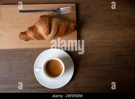 Croissant with espresso in white cup on wooden table Stock Photo