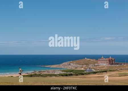 A golfer walks along Newquay Golf Course overlooking Fistral Beach and The Headland Cornwall hotel. Stock Photo