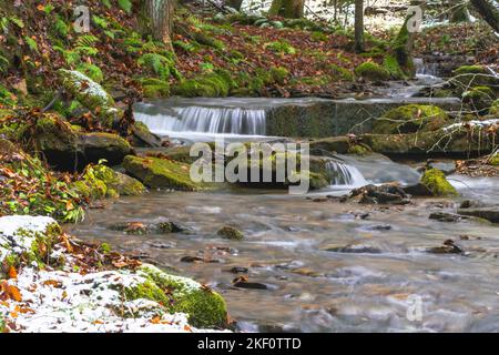 Fresh snow in the woods stream moving water long exposure, copy space outdoors winter background Stock Photo