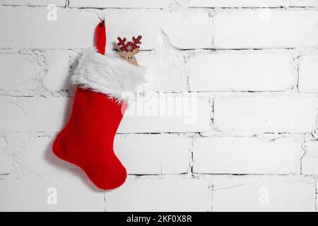 christmas sock with deer decoration hanging on white brick wall background. copy space Stock Photo