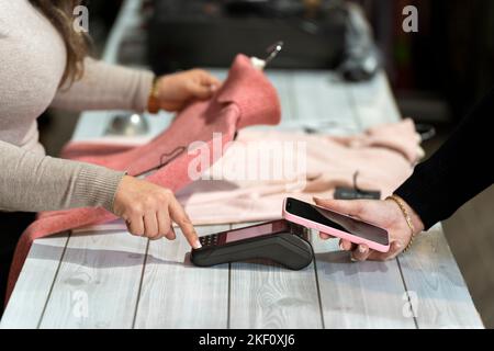 Counter with a customer paying with smartphone in a clothing shop Stock Photo