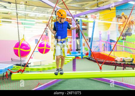 Boy in protective gear holding safety rope and passing obstacle course Stock Photo