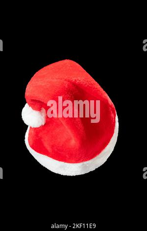 Red and white christmas hat on black background. Santa claus cap on the plain dark background. Stock Photo