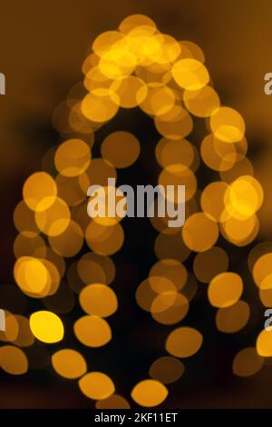 Blurry Christmas lights on the Christmas tree. Pine tree decorated with shining garland. Stock Photo