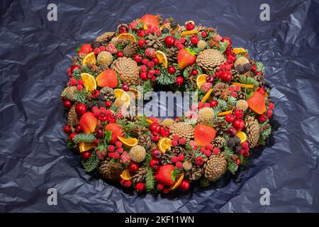 Colorful wreath in the blue background. Garland decorated with fruit and berries on the dark surface. Stock Photo