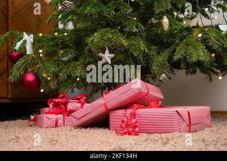 Wrapped gifts under the christmas tree. Presents under the decorated pine tree. Stock Photo