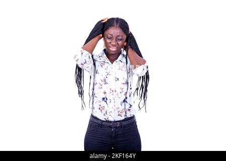 a young woman in a shirt standing on a white background with braids feeling pain in the head. Stock Photo