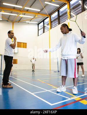 Sports Students: Badminton Mixed Doubles. Teenagers in their college gym under the supervision of their teacher. From a series of related images. Stock Photo