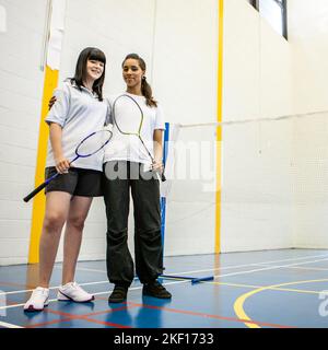 Sports Students: Badminton Partners. Teenage girls ready to begin their game on court. From a series of related images. Stock Photo