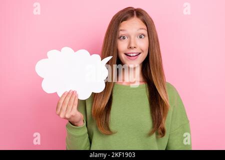 Photo of impressed funky school girl dressed green sweatshirt holding speaking bubble empty space isolated pink color background Stock Photo
