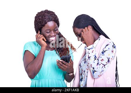 of young businesswomen standing on white background listening to music using cellphone and headphones smiling. Stock Photo