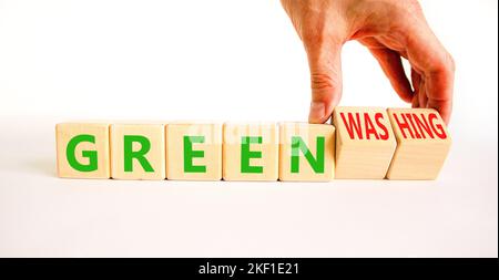 Green or greenwashing symbol. Concept words Green and Greenwashing on wooden cubes. Businessman hand. Beautiful white table white background. Business Stock Photo