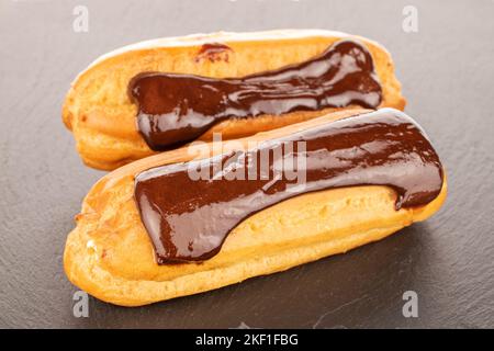 Two sweet eclairs on slate stone, macro. Stock Photo