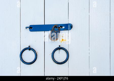 Old padlcok and steel rings on white painted doors. Stock Photo