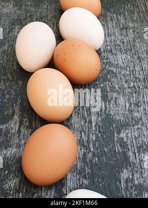 White and brown eggs of domestic chickens. Laying eggs of hen close-up on dark green noisy background. Farm eco-friendly product. Stock Photo