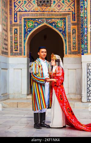 Samarkand, Uzbekistan - April 18, 2021: Bride and groom in traditional uzbek dresses at Registan ancient city, Samarkand city in Uzbekistan Stock Photo