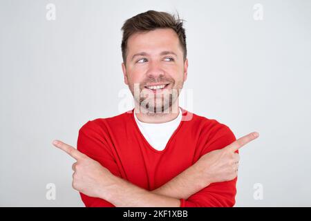 Smiling man standing with crossed hands and pointing to copy space on both sides Stock Photo
