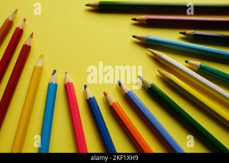 a set of colored pencils on a yellow table. Stock Photo