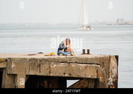 A young romantic couple on the sea wall on the Tejo Promenade, River Tagus Lisbon, Portugal. Stock Photo