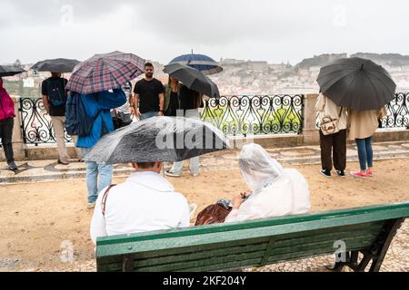 Heavy rain sweeps in and tourists have to take shelter as they take pictures and selfies at Miradouro de São Pedro de Alcântara in Lisbon, Portugal. Stock Photo