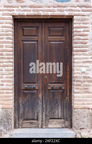 Old wooden door in a brick wall Stock Photo