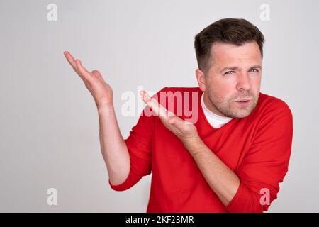 Doubtful man points at corner, feels hesitant about something Stock Photo