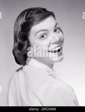 1960s 1950s SMILING BRUNETTE TEENAGE GIRL WITH PAGEBOY HAIR HAIRSTYLE SMILING LOOKING AT CAMERA OVER HER SHOULDER - g128 HAR001 HARS WELCOME COMMUNICATION LAUGH YOUNG ADULT PLEASED JOY LIFESTYLE SATISFACTION FEMALES STUDIO SHOT HEALTHINESS HOME LIFE COPY SPACE PERSONS TEENAGE GIRL EXPRESSIONS B&W EYE CONTACT BRUNETTE BUG-EYED HAPPINESS HEAD AND SHOULDERS CHEERFUL DISCOVERY EXCITEMENT HAIRSTYLE SMILES CONNECTION JOYFUL STYLISH TEENAGED DOTTED SWISS WIDE-EYED PAGEBOY YOUNG ADULT WOMAN BLACK AND WHITE CAUCASIAN ETHNICITY HAR001 OLD FASHIONED Stock Photo