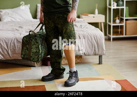 Close up of military veteran with prosthetic leg wearing army uniform in home setting, copy space Stock Photo