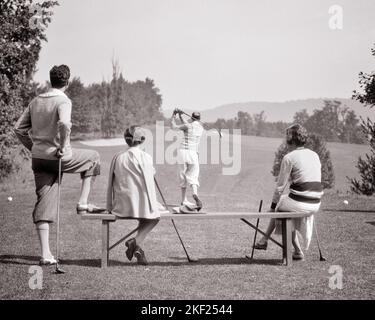 1920s 1930s GROUP OF MEN AND WOMEN AT TEE BOX OF GOLF COURSE WOMEN SITTING ON BENCH - g3667 HAR001 HARS TEE COPY SPACE FULL-LENGTH HALF-LENGTH LADIES PERSONS MALES GOLFING ATHLETIC B&W CLUBS MASSACHUSETTS COURSE GOLFERS SPORTY STYLES AND RECREATION COUNTRY CLUB FAIRWAY BERKSHIRES REAR VIEW UPSCALE CONCEPTUAL FROM BEHIND LINKS STYLISH PLUS FOURS BACK VIEW FASHIONS MA YOUNG ADULT MAN YOUNG ADULT WOMAN BLACK AND WHITE CAUCASIAN ETHNICITY GOLF COURSE HAR001 OLD FASHIONED Stock Photo