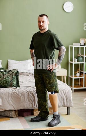 Full length portrait of military veteran with prosthetic leg wearing army uniform and looking at camera Stock Photo