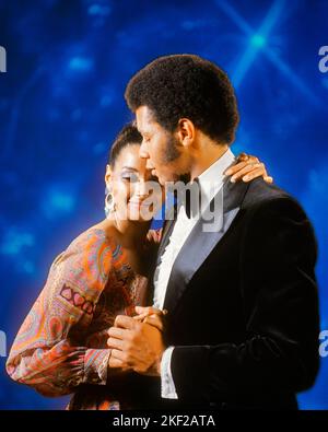 1970s AFRICAN AMERICAN COUPLE MAN TUXEDO WOMAN EVENING DRESS DANCING EMBRACING - kd2723 HAR001 HARS EVENT HUG LADIES PERSONS AFRO CARING MALES EMBRACING DATING TUX AFRICAN-AMERICANS AFRICAN-AMERICAN HAIRSTYLE BLACK ETHNICITY TO ATTRACTION FACIAL HAIR RELATIONSHIPS COURTSHIP PERSONAL ATTACHMENT POSSIBILITY AFFECTION EMOTION SIDEBURNS SOCIAL ACTIVITY COURTING HAR001 OLD FASHIONED AFRICAN AMERICANS Stock Photo