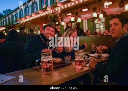 Huge mugs and smiling people at outdoor tables, French fries and hamburgers in the free area (access is limited in pavilions with live music) Stock Photo