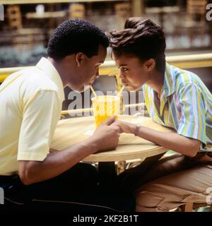 1980s ROMANTIC AFRICAN-AMERICAN COUPLE BOY AND GIRL FACE TO FACE HOLDING HANDS SHARING A SOFT DRINK WITH TWO STRAWS - kf20615 TEU001 HARS OLD FASHION 1 STYLE COMMUNICATION YOUNG ADULT STRONG JOY LIFESTYLE FEMALES COPY SPACE FRIENDSHIP HALF-LENGTH LADIES PERSONS CARING MALES TEENAGE GIRL TEENAGE BOY STRAWS DATING SUCCESS HAPPINESS LEISURE AFRICAN-AMERICANS AFRICAN-AMERICAN EXCITEMENT BLACK ETHNICITY HOLDING HANDS TO ATTRACTION RELATIONSHIPS FACE TO FACE CONNECTION COURTSHIP CONCEPTUAL CONSUME CONSUMING HYDRATION PERSONAL ATTACHMENT POSSIBILITY AFFECTION EMOTION REFRESHING SOCIAL ACTIVITY Stock Photo