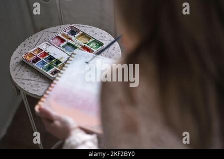 closeup of a woman's left hand holding a ring binder notebook and a brush sliding over it Stock Photo