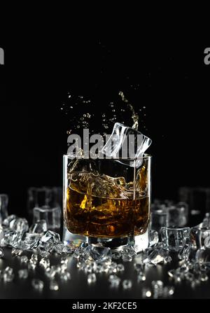 Premium Photo  Glass with whiskey and falling ice cube with splashes