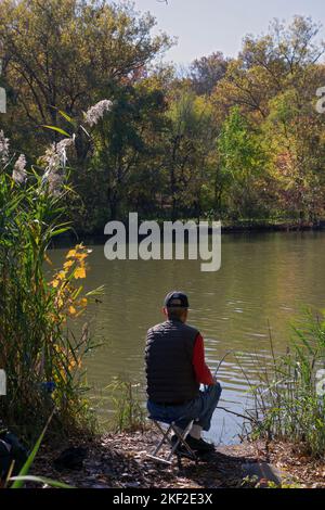 An unidentified man fishes at the lake in Kissena Park in Queens, New York City Stock Photo