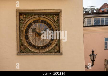 Estonia, Tallinn - July 21, 2022: Closeup of sculpted and painted artful clock on yellow facade of Holy Spirit Church Stock Photo