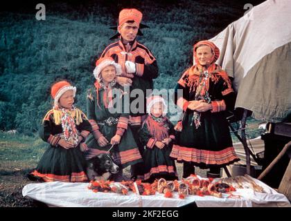 1950s SAMI SAAMI FAMILY FIVE SEMI-NOMADIC HERDERS MOTHER FATHER THREE CHILDREN IN NATIVE DRESS WITH DOG AND DISPLAYING CRAFTS - kr3765 LAN001 HARS NATIVE ETHNIC NOSTALGIC PAIR COMMUNITY COLOR MOTHERS MAGIC OLD TIME NOSTALGIA OLD FASHION 1 JUVENILE STYLE YOUNG ADULT TEAMWORK MYSTERY FAMILIES LIFESTYLE FIVE HISTORY FEMALES MARRIED 5 RURAL SPOUSE HUSBANDS HOME LIFE COPY SPACE FRIENDSHIP HALF-LENGTH LADIES CRAFTS DAUGHTERS PERSONS MALES FATHERS PARTNER EYE CONTACT COLORFUL MAMMALS LOCAL COLOR AND CANINES DADS OCCUPATIONS CONNECTION NOMADIC STYLISH ARCTIC CANINE CREATIVITY GROWTH JUVENILES MAMMAL Stock Photo
